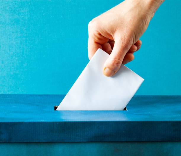 Person putting paper in ballot box for election