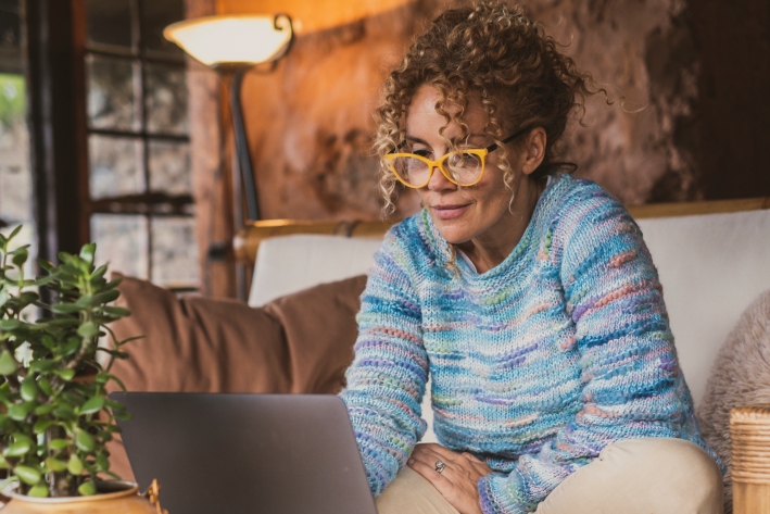 Woman sitting on couch, looking at computer