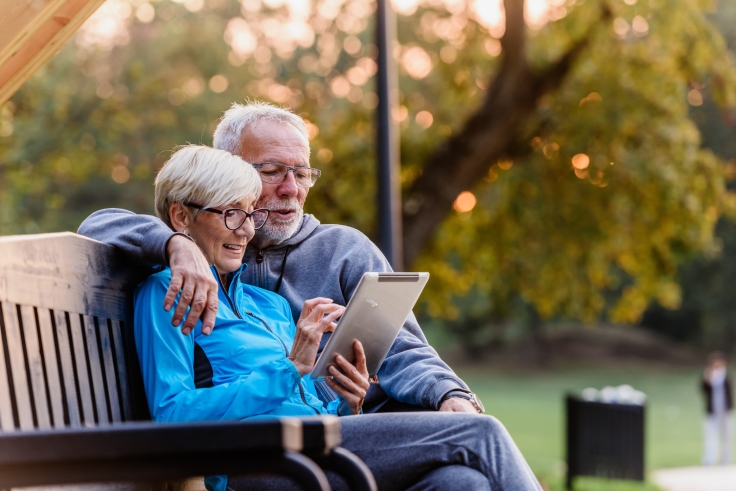 Couple sitting on bench with tablet