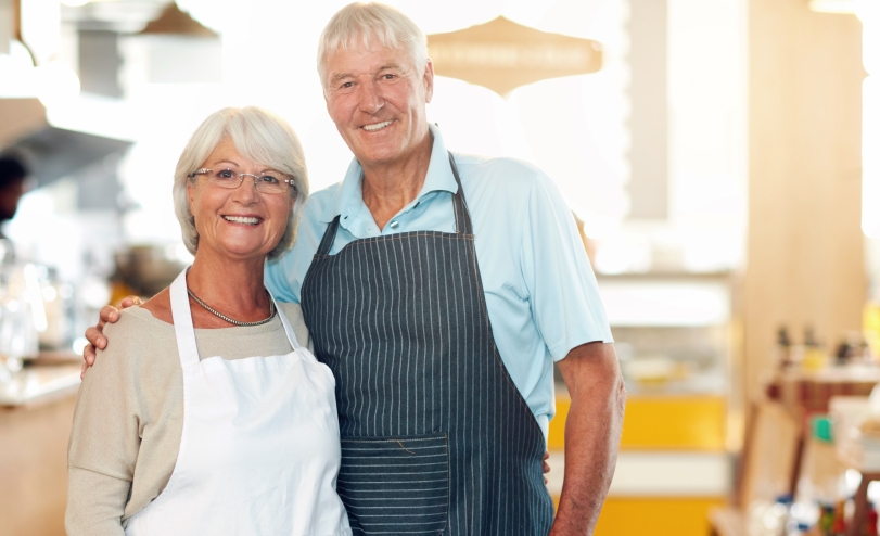 Two business owners in aprons posing for a photo