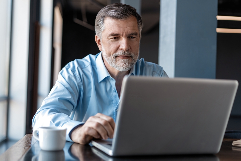 Mature adult looking at laptop, revisiting the 2025 market outlook