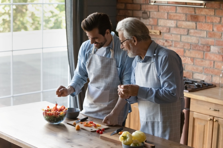 Father and adult son cooking together in the kitchen