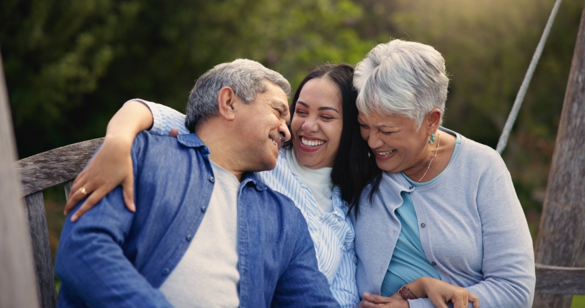 Woman sitting on a bench laughing with her parents